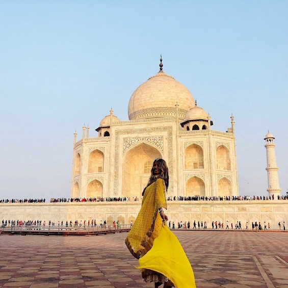 Taj Mahal med en person i en gul klänning som går framför byggnaden. 5