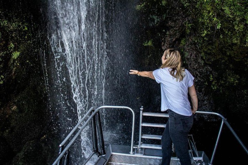 A person standing on a metal staircase overlooking a waterfall. 2