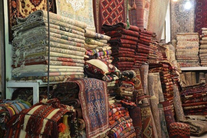 Una variedad de textiles, incluyendo alfombras y tapetes doblados, exhibidos en una tienda. 4