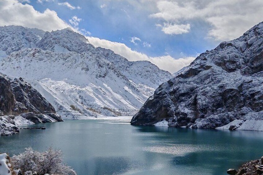 Un lac de montagne recouvert de neige, aux eaux d’un bleu limpide, entouré de sommets enneigés. 2