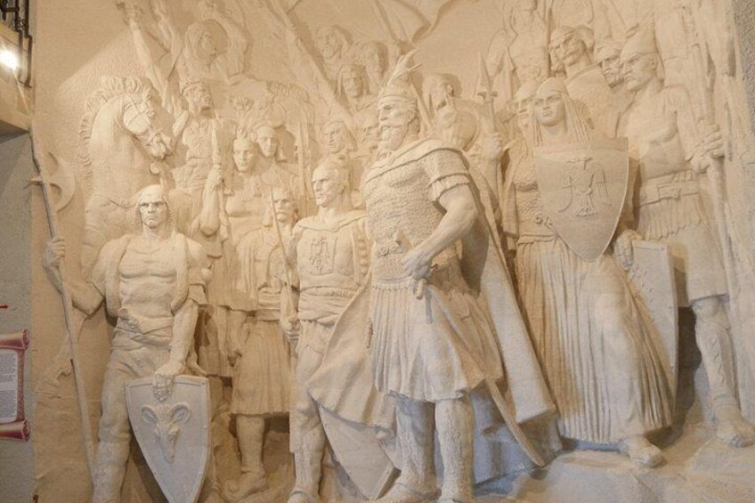 A detailed stone carving of a historical battle scene with warriors, shields, and a central figure in armor. 2