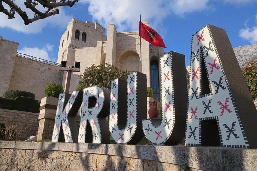 A building with a flag, large letters spelling 'KRUGA,' and a patterned design. 1