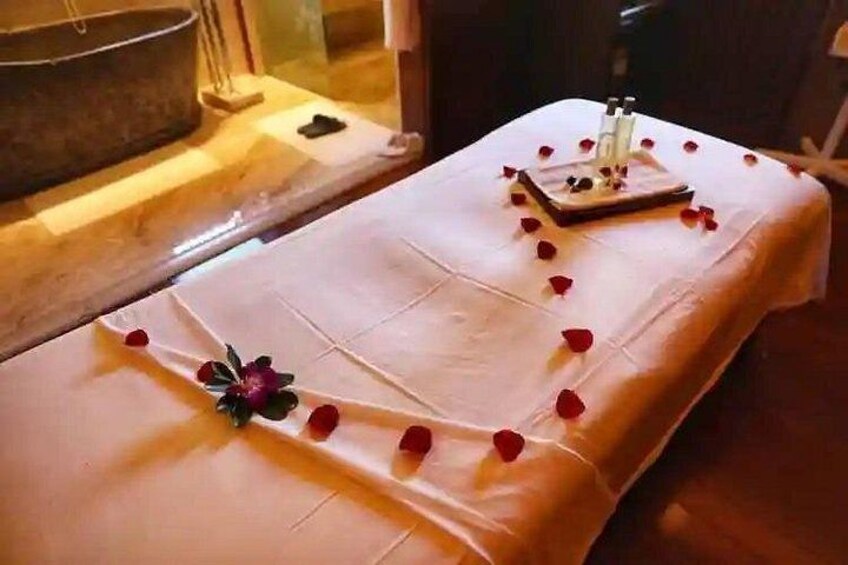 A massage table with rose petals and a flower. 2