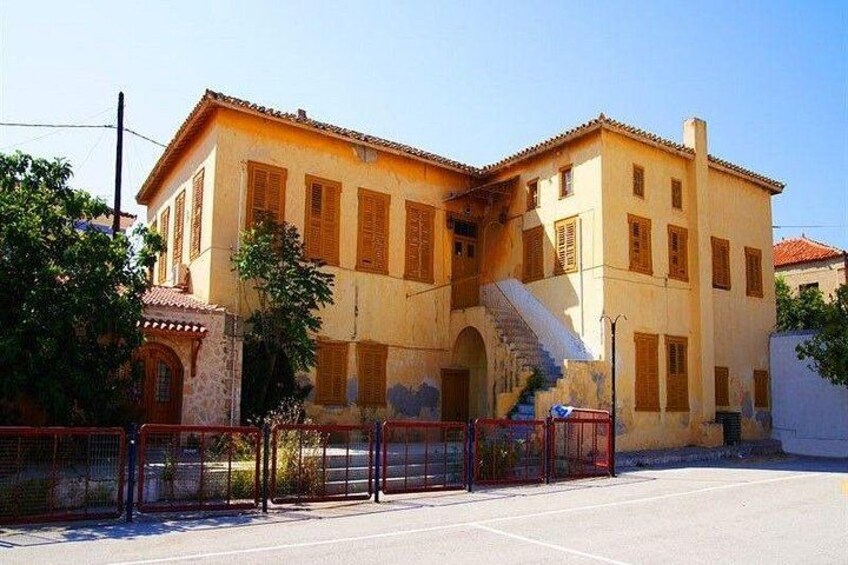A two-story building with a yellow facade, wooden shutters, and a staircase leading to the upper floor. 5
