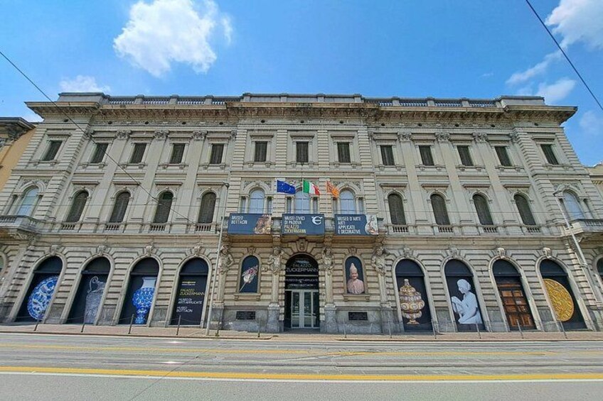 Un edificio histórico con varias banderas, ventanas arqueadas y una entrada central. 2