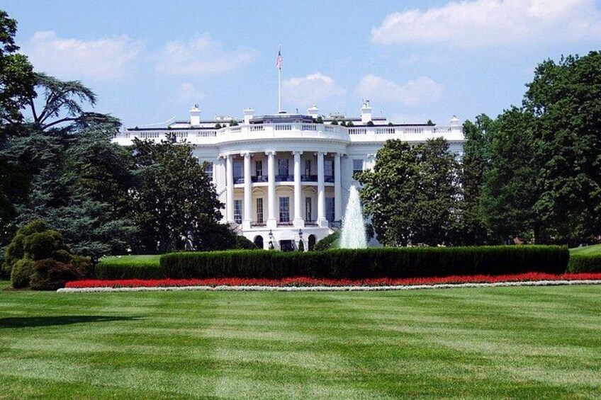 La Casa Blanca con una fuente en primer plano y un césped bien cuidado. 2