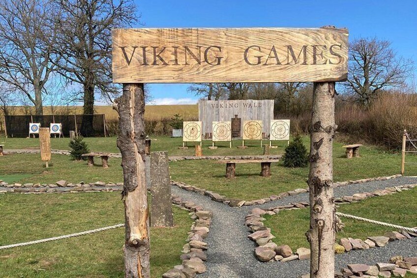 En träskylt med texten ”VIKINGSPEL” och pilar i bakgrunden. 3