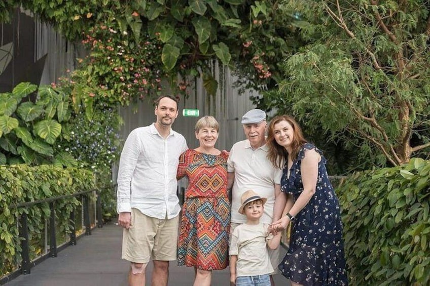 Un grupo de personas de pie en un jardín con abundante vegetación y una valla de metal. 2