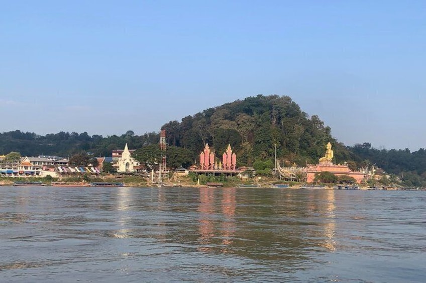 A river with a temple complex on a hill, including a golden statue. 3