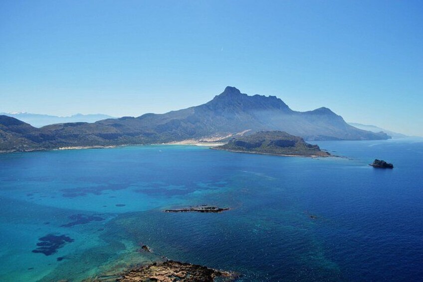 Un paysage côtier caractérisé par des eaux d’un bleu limpide, une montagne imposante et une petite île. 1