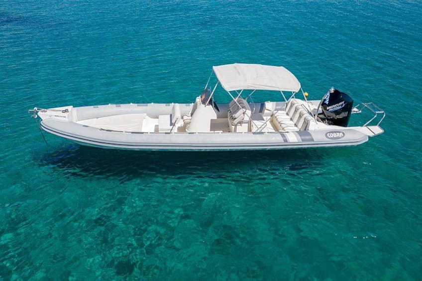 Un bateau à moteur blanc, doté d’un auvent, flotte sur une eau turquoise et cristalline. 2