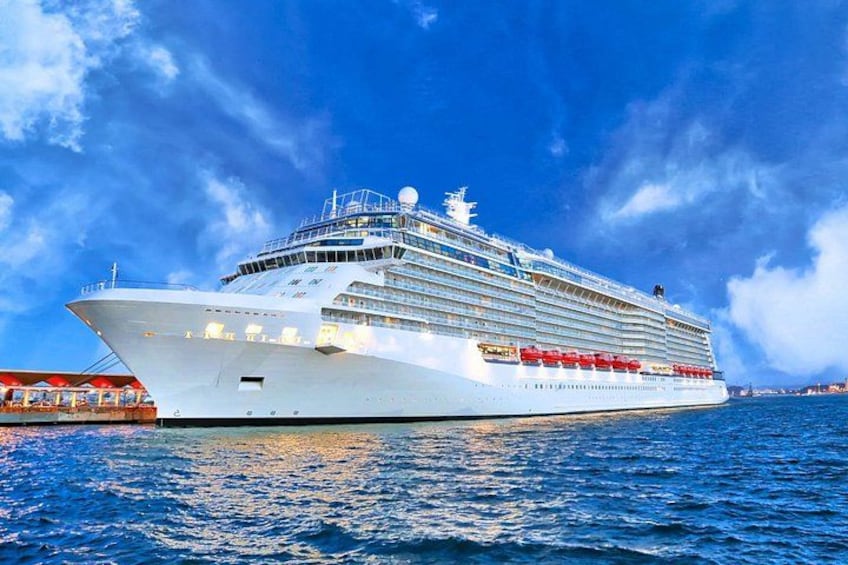 A large cruise ship docked at a port with a clear blue sky in the background. 1