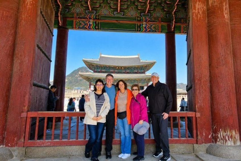 A group of people standing in front of a traditional building with a red roof and ornate decorations. 3