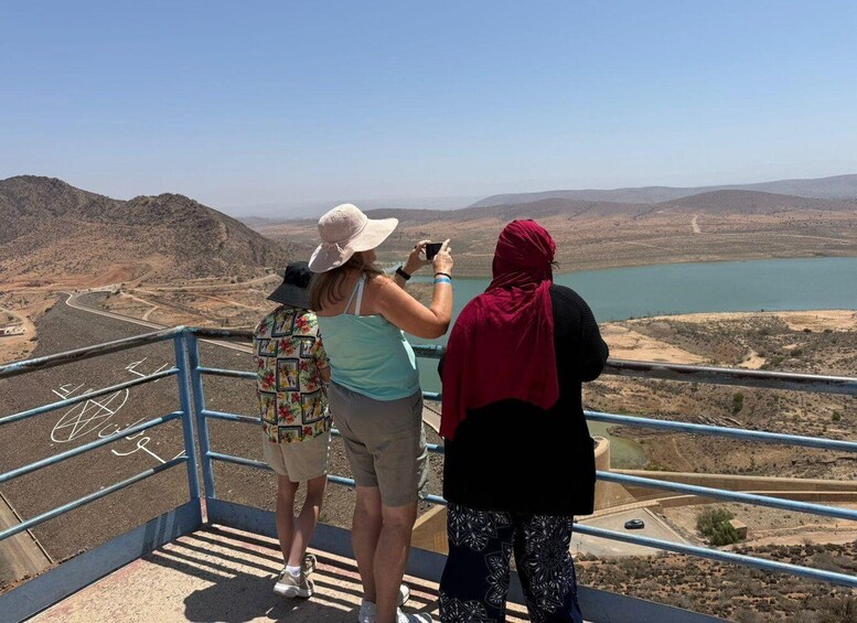 Three people taking a photo of a lake from a viewing platform. 1