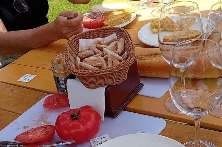 A table with a basket of bread, a tomato, and wine glasses. 3