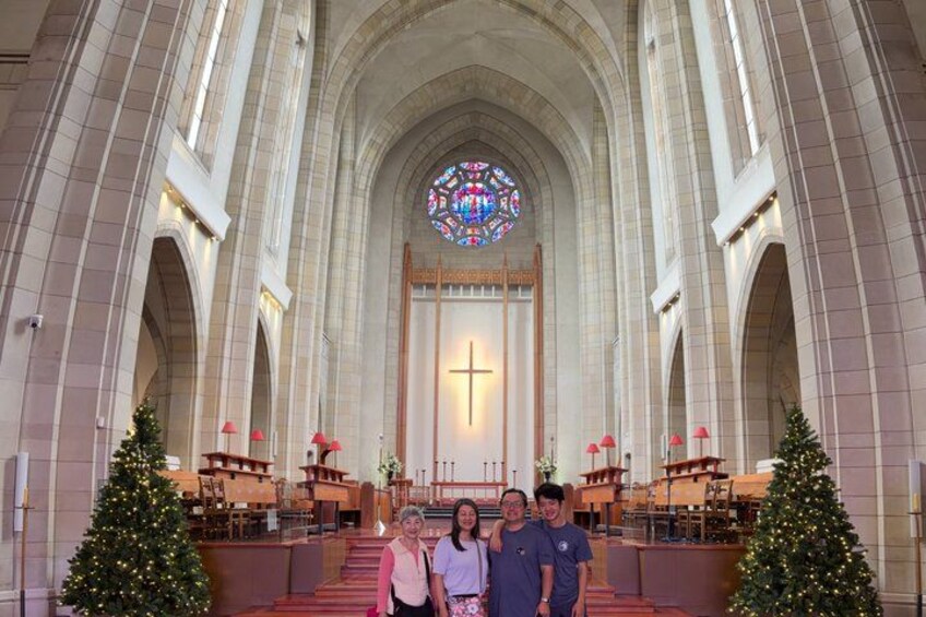 L’intérieur d’une église, avec une grande fenêtre en vitrail, des voûtes en arc et des sapins de Noël. 5