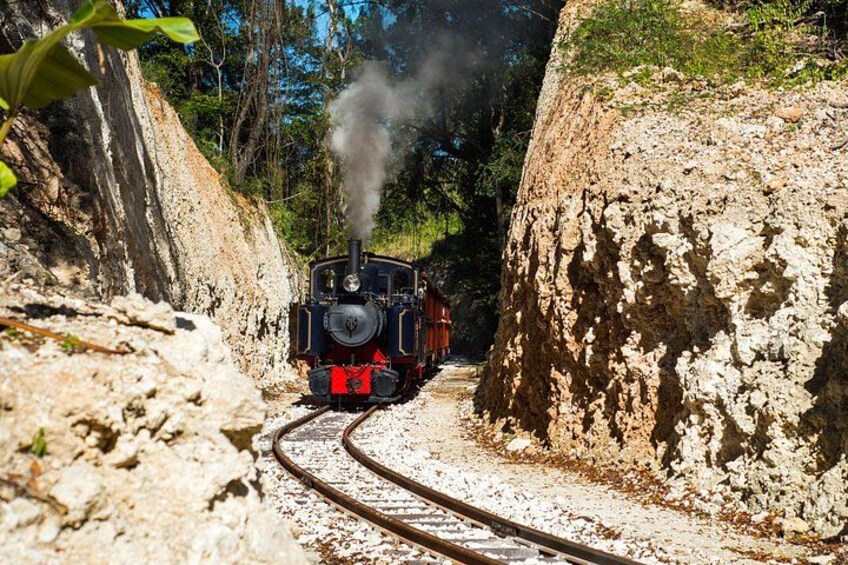 A steam locomotive on a narrow railway track surrounded by rocky terrain. 5