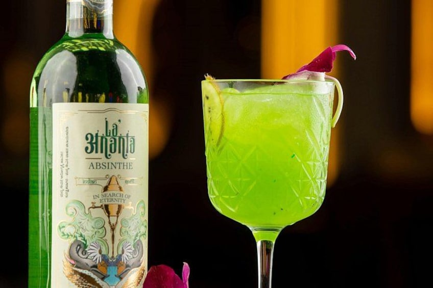 Una botella de ajenjo y un cóctel verde con decoración. 1