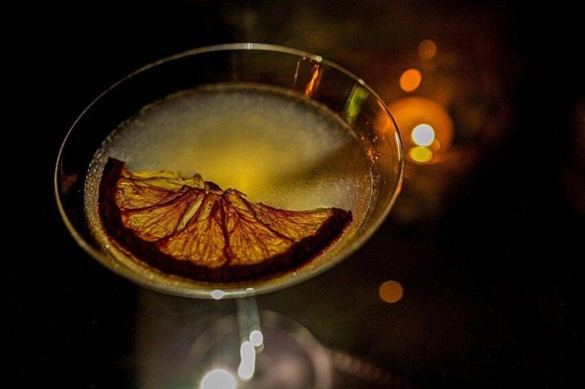Un vaso con un líquido oscuro y una rodaja de naranja deshidratada. 3