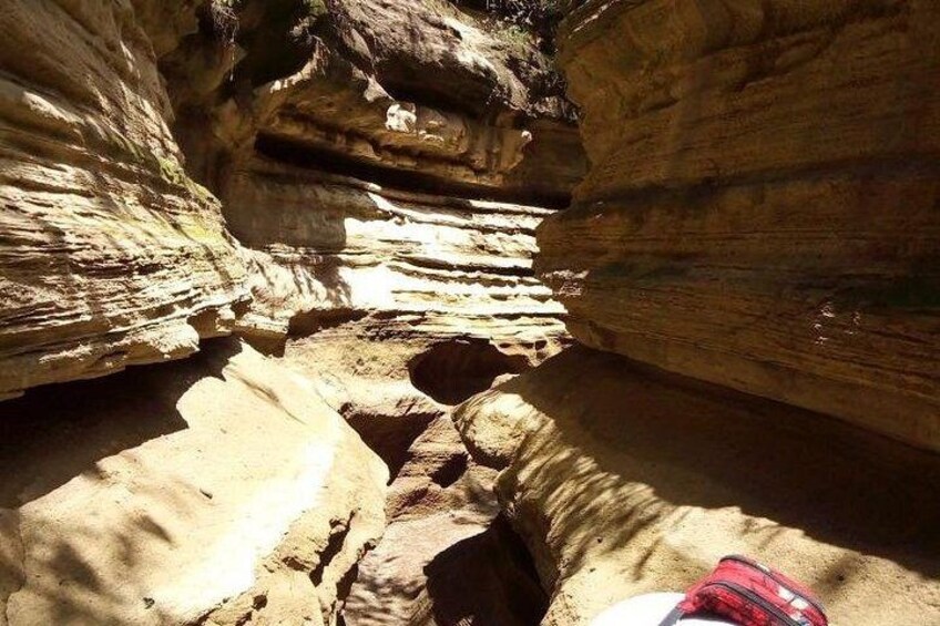 A narrow canyon with layered rock formations and a backpack on the ground. 2