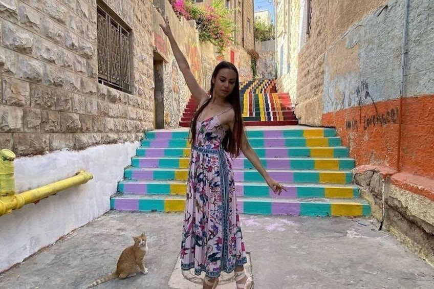 A person standing in a narrow alleyway with colorful steps leading up to a building. 2