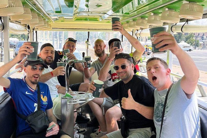 A group of people on a bus, holding up cups and taking photos. 1
