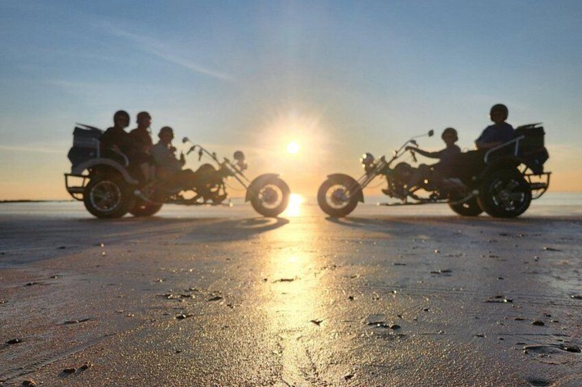 Two motorcyclists on a beach at sunset. 2