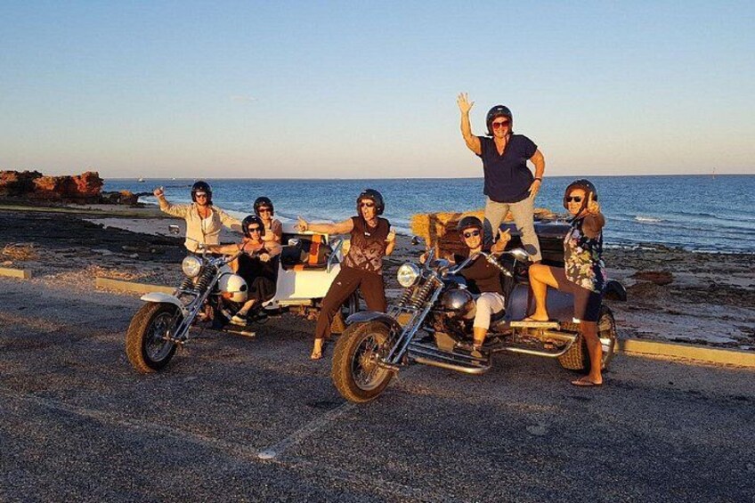 A group of people on a beach with a motorcycle and a trailer. 4
