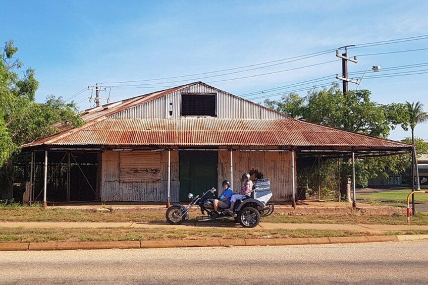 A rusted metal building with a corrugated roof, a motorcycle parked in front, and a clear sky. 5