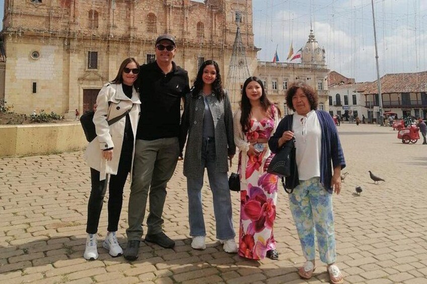 A group of people standing in a square with a historic building in the background. 2