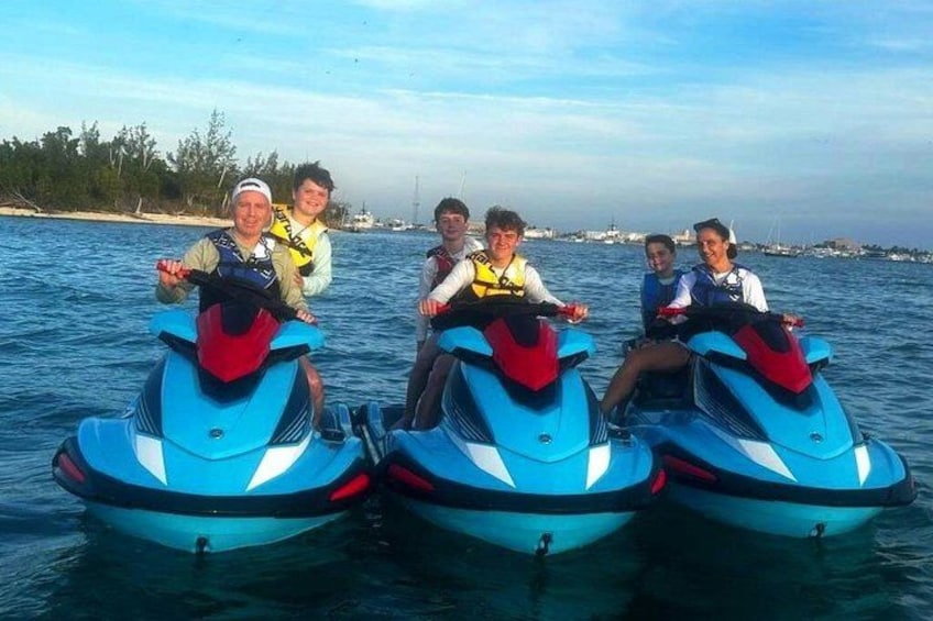 Quatre personnes sur des scooters des mers sur une étendue d’eau, avec une côte en arrière-plan. 3
