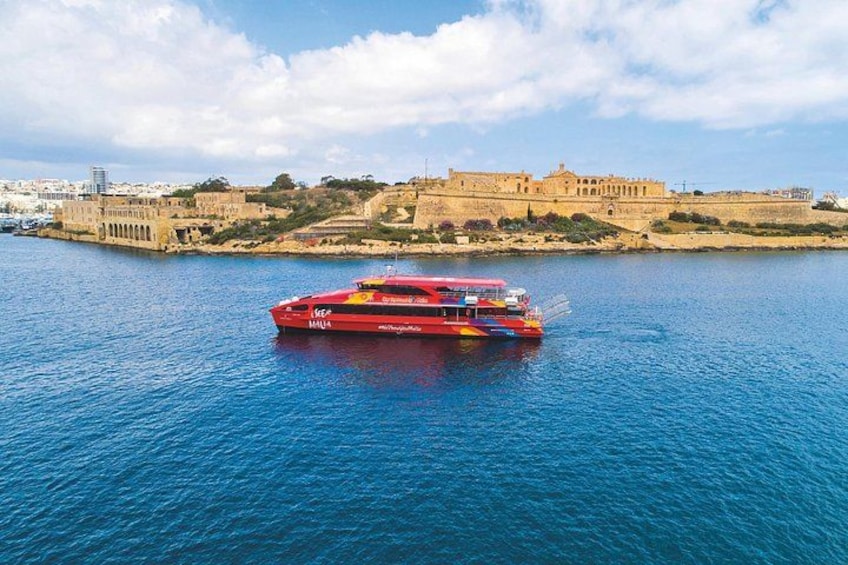 A red boat on a calm sea with a historic building in the background. 2