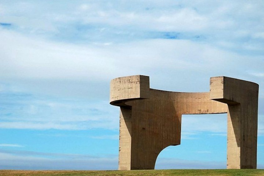 Une grande sculpture en béton, située dans un champ ouvert, sous un ciel dégagé. 2
