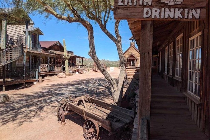 A wooden building with a sign reading 'EXTRA DRINKIN' and a wooden cart in front. 2