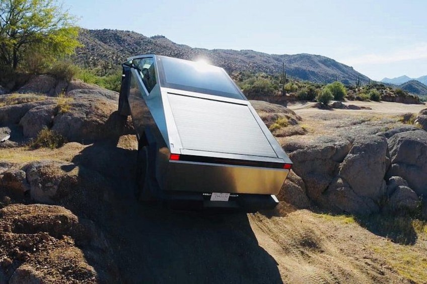 A vehicle parked on a rocky terrain with a mountainous landscape in the background. 1
