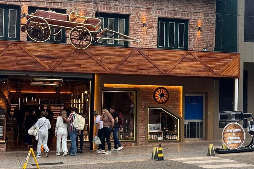 Un edificio de ladrillo con fachada de madera y decoración de rueda de carruaje. Hay gente reunida afuera. 2