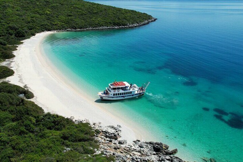 Una barca su una spiaggia turchese con un litorale roccioso e vegetazione rigogliosa. 4