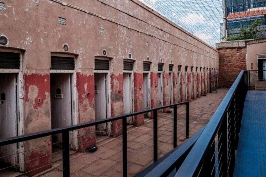Una fila di edifici antichi e scoloriti, con vernice rossa e bianca, un corrimano in metallo e cielo sereno. 2