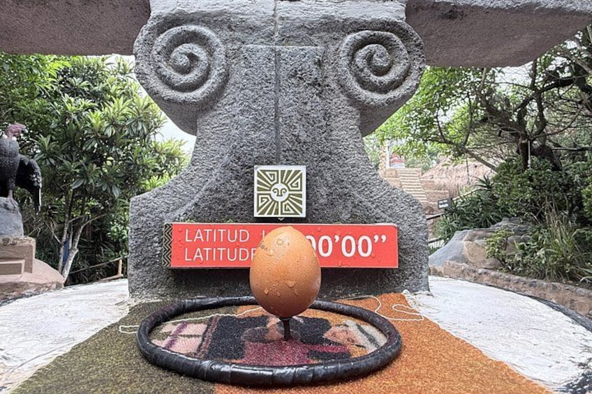 A stone sculpture with a spherical object in front, surrounded by a patterned mat. 2