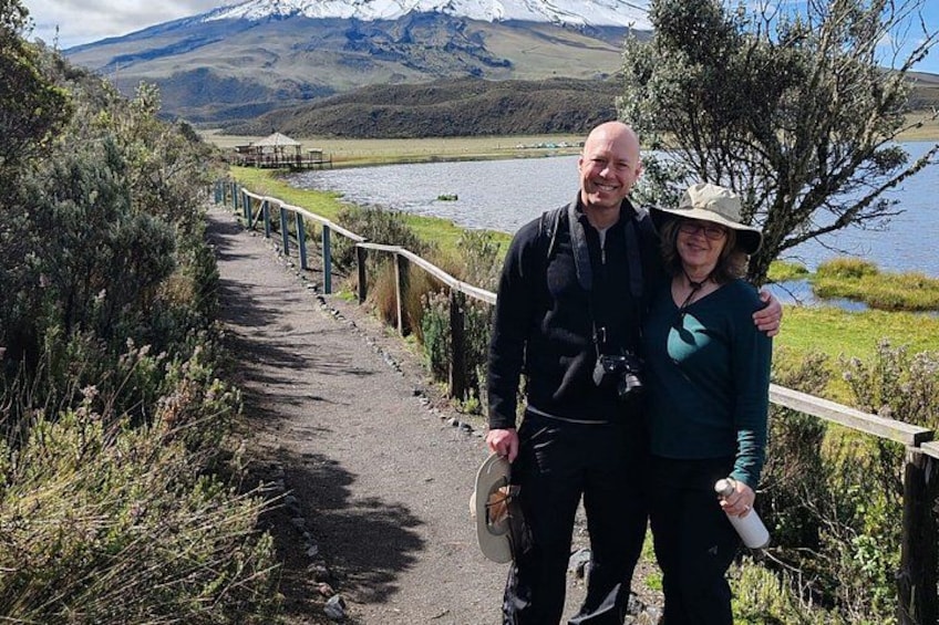 A paved path with a railing, a body of water, and a mountainous landscape in the background. 4