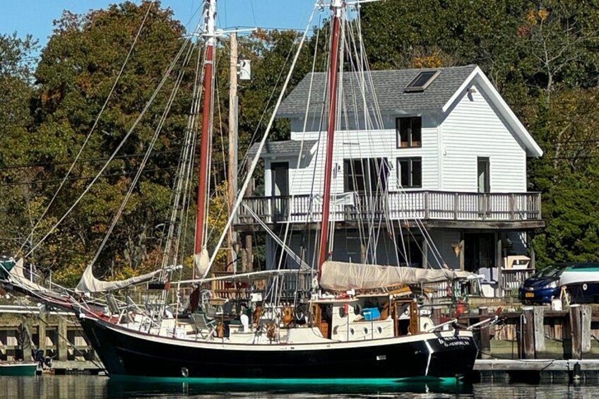 Un velero amarrado en el puerto deportivo, con una casa al fondo. 4