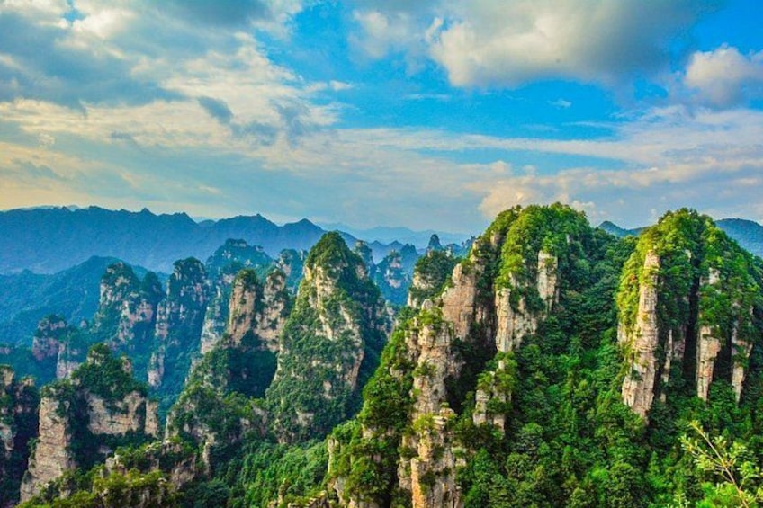 A mountainous landscape with prominent limestone peaks and dense green vegetation. 2
