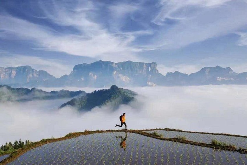 A person running on terraced fields with mountains in the background. 3