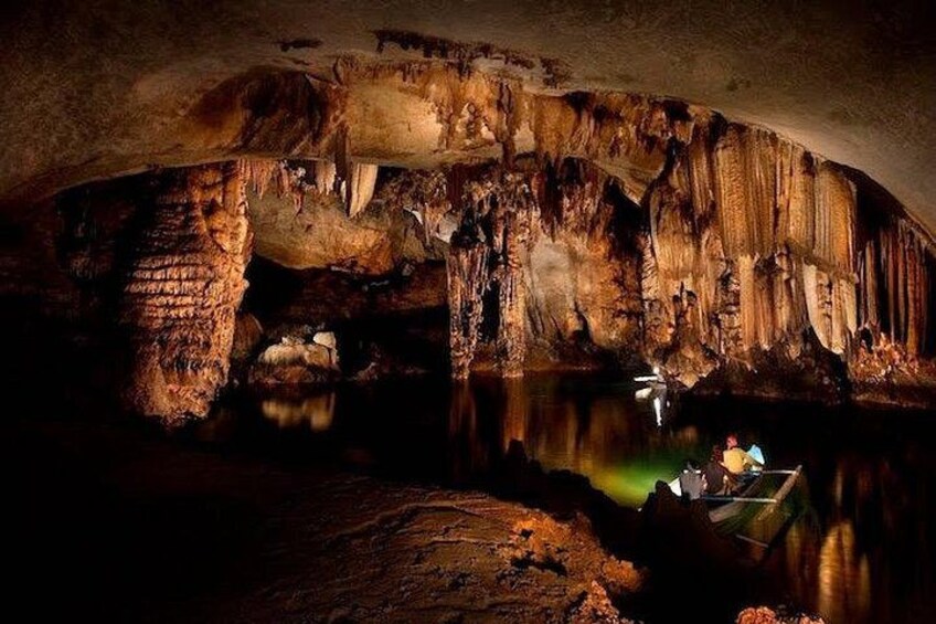 Une grotte avec des stalactites, une étendue d’eau et une personne dans un bateau. 3