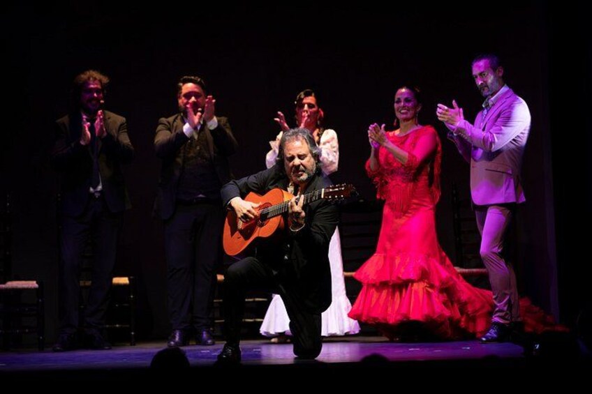 A group of people performing on stage with a guitar player in the center. 4