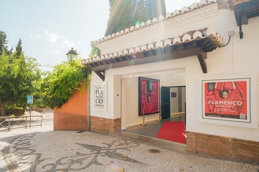 A theater entrance with a red carpet, posters, and a sign indicating a Flamenco event. 2