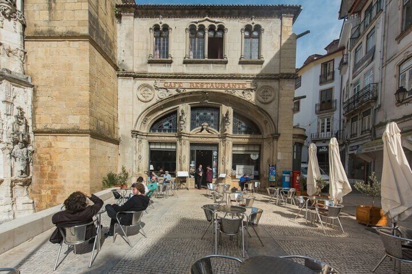 Un edificio storico con un bar e un ristorante, posti a sedere all'aperto con ombrelloni e pavimentazione in pietra. 4