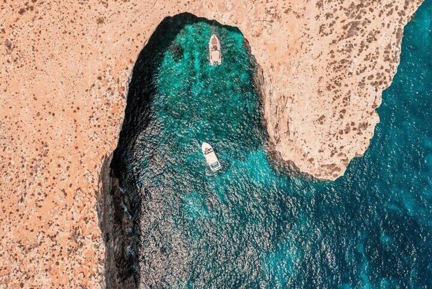 An aerial view of a coastal area with a boat in the water and a rocky shoreline. 1