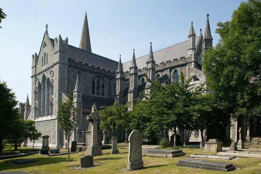 A large Gothic-style church with pointed spires and a cemetery in front. 1