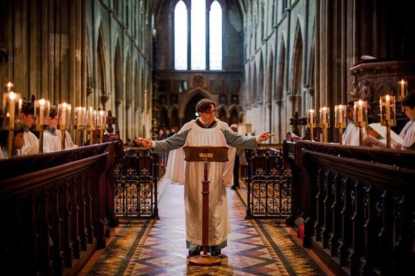 A person in religious attire standing in a church aisle with candles. 3